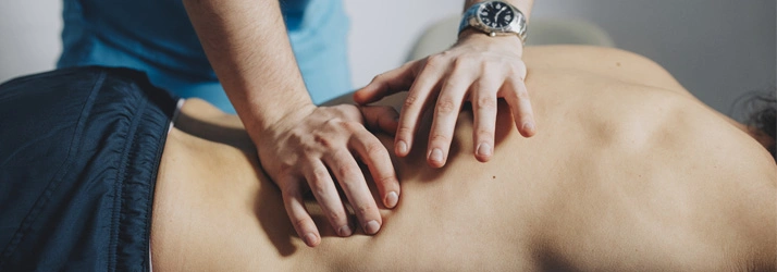 Chiropractor providing manual adjustment therapy on a patient’s lower back