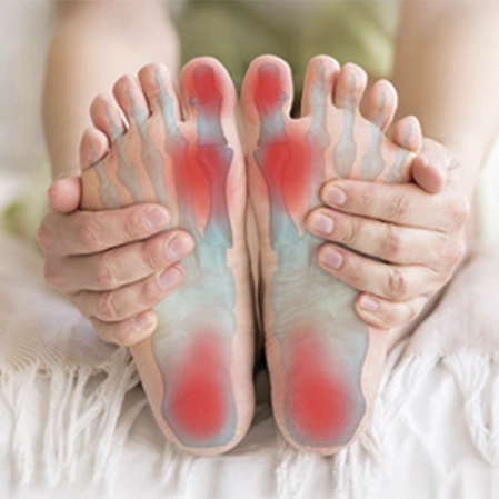 Hands holding feet with highlighted pressure points in red and blue on the soles.