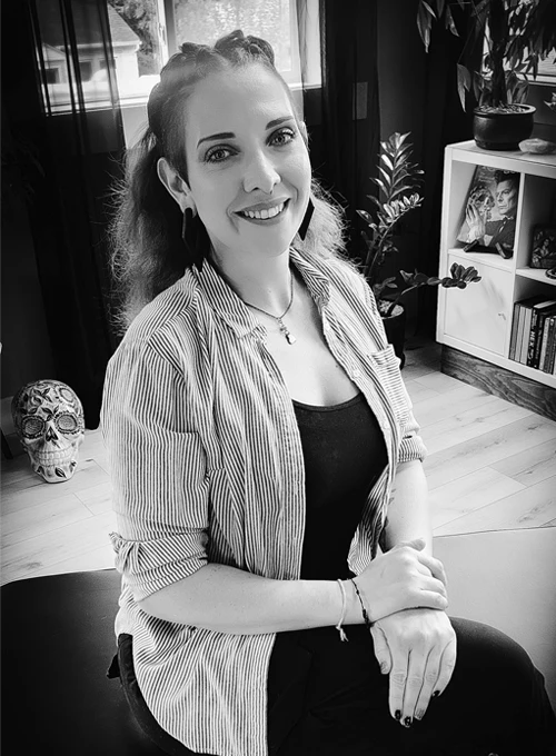 Dr. Emme Lyda DC sitting on a treatment table in a chiropractic clinic, smiling at the camera.